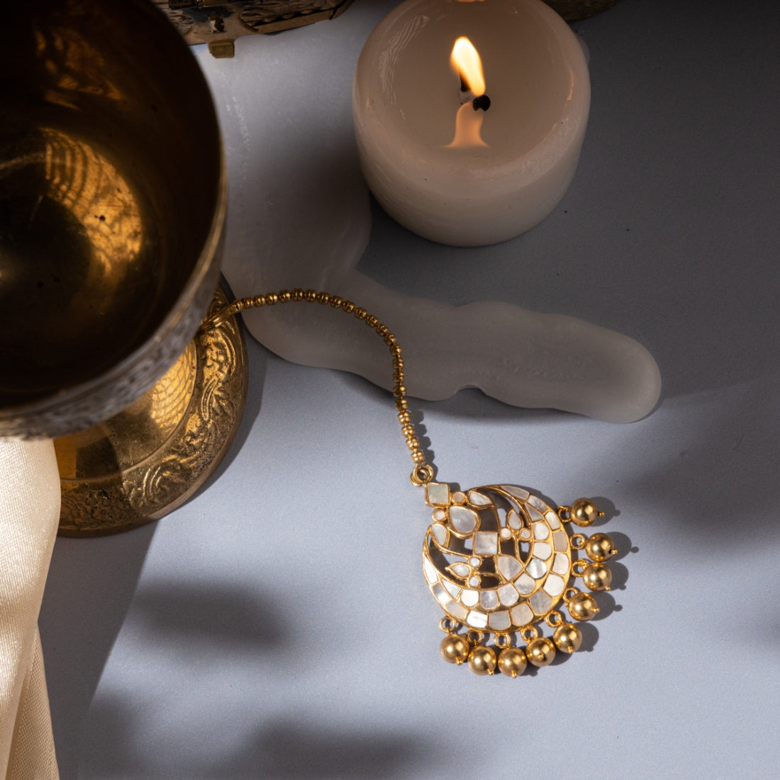 Mother-of-pearl maang tikka featuring hanging gold beads and semi-precious stones.