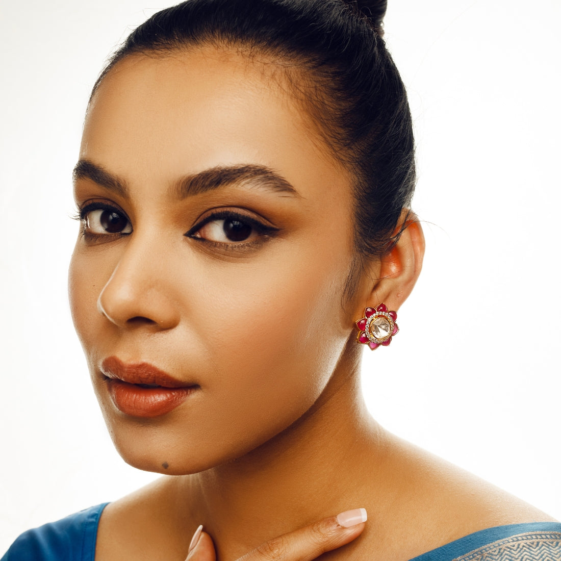 Ruby red stud earrings featuring a central high-quality polki-style gem surrounded by smaller ruby red stones in a sunflower pattern.