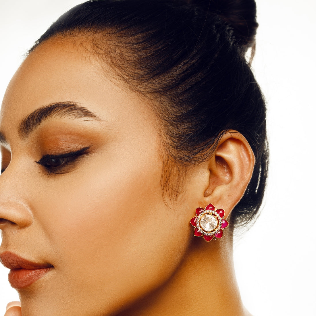 Ruby red stud earrings featuring a central high-quality polki-style gem surrounded by smaller ruby red stones in a sunflower pattern.