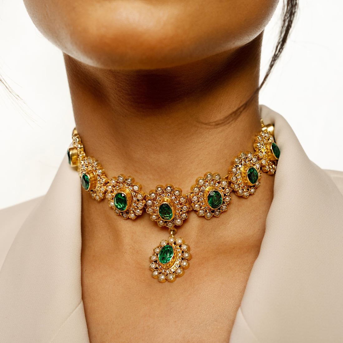 Gold-plated choker necklace featuring round emerald green stones arranged in a sunflower pattern.