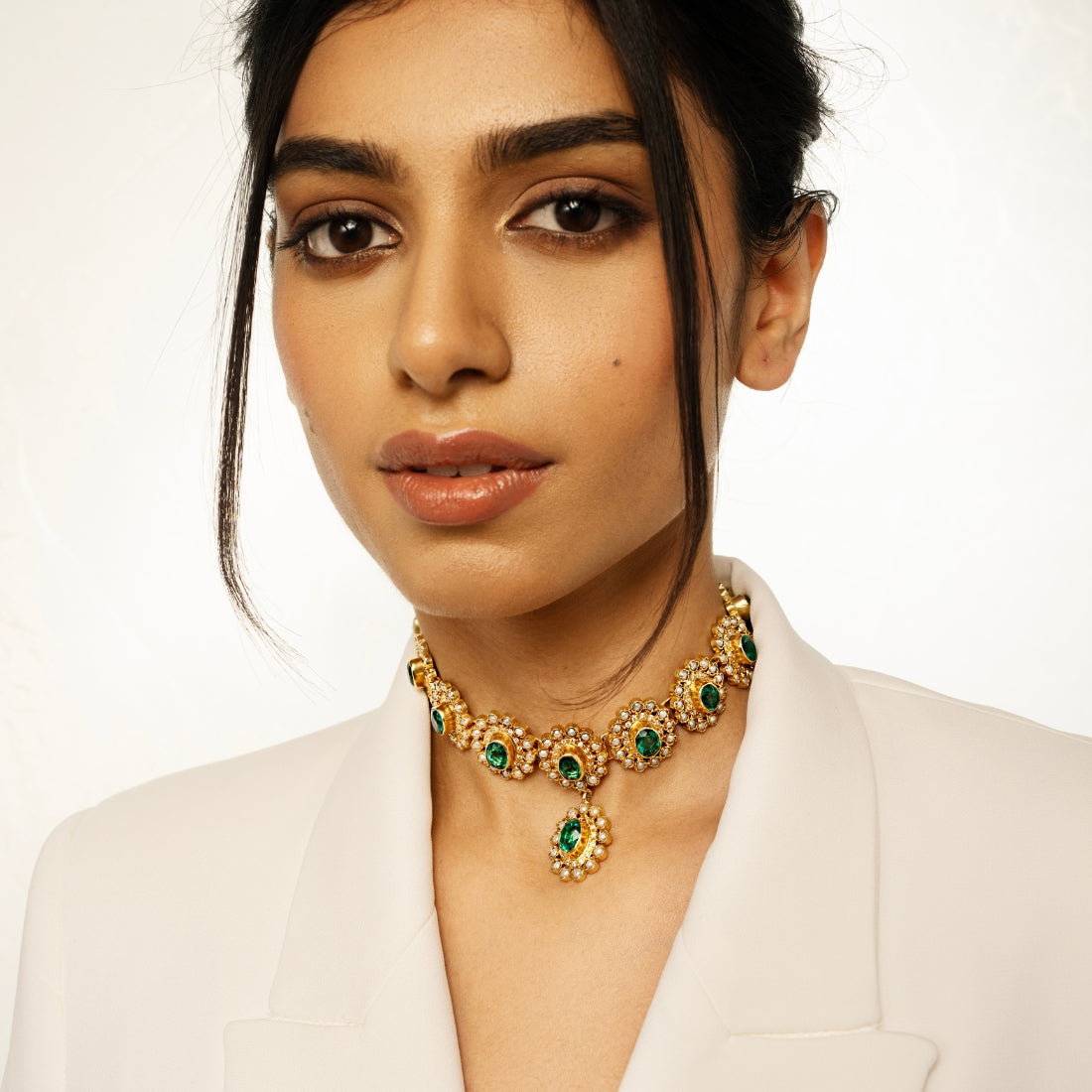 Gold-plated choker necklace featuring round emerald green stones arranged in a sunflower pattern.