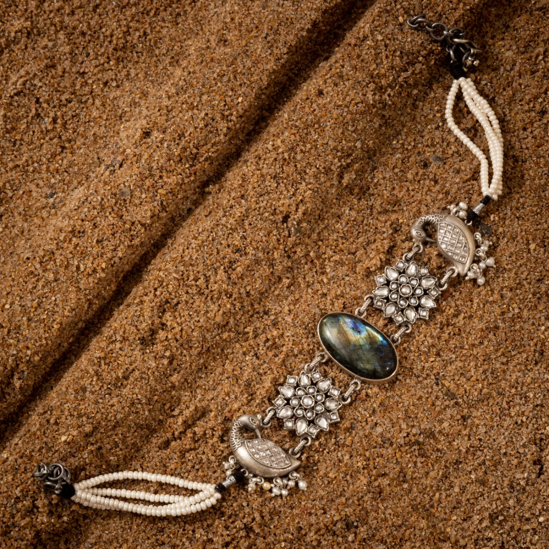 Oxidized silver choker necklace featuring a peacock motif with semi-precious stone accents on a grainy background.