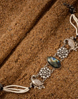 Oxidized silver choker necklace featuring a peacock motif with semi-precious stone accents on a grainy background.