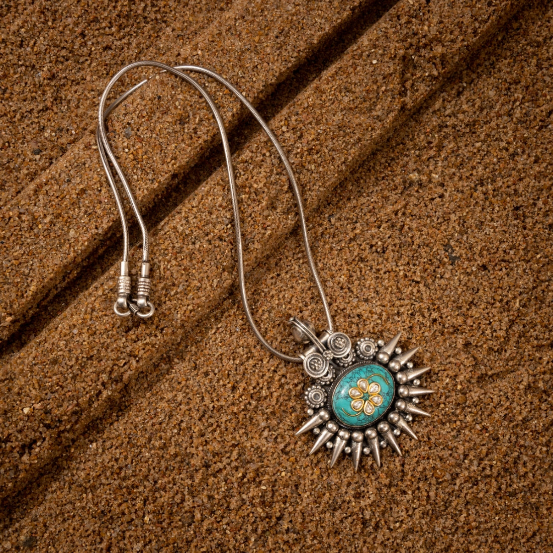 Turquoise pendant crafted from sterling silver featuring a genuine turquoise gemstone on a grainy background.