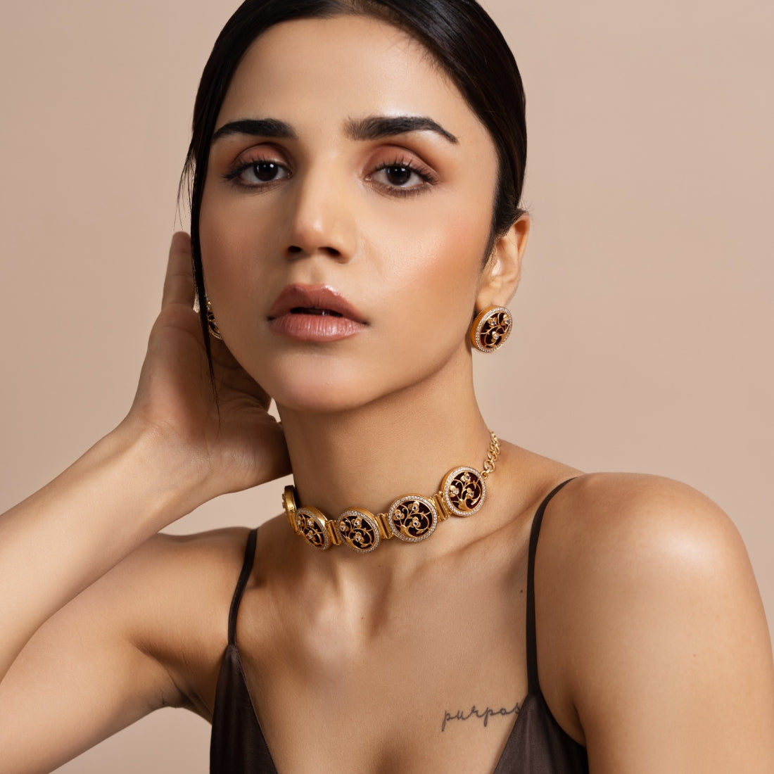 Silver choker necklace and stud earrings set featuring gold plating. The choker has coin-shaped pendants with Art Deco flora and fauna designs studded with CZ stones and black enamel.