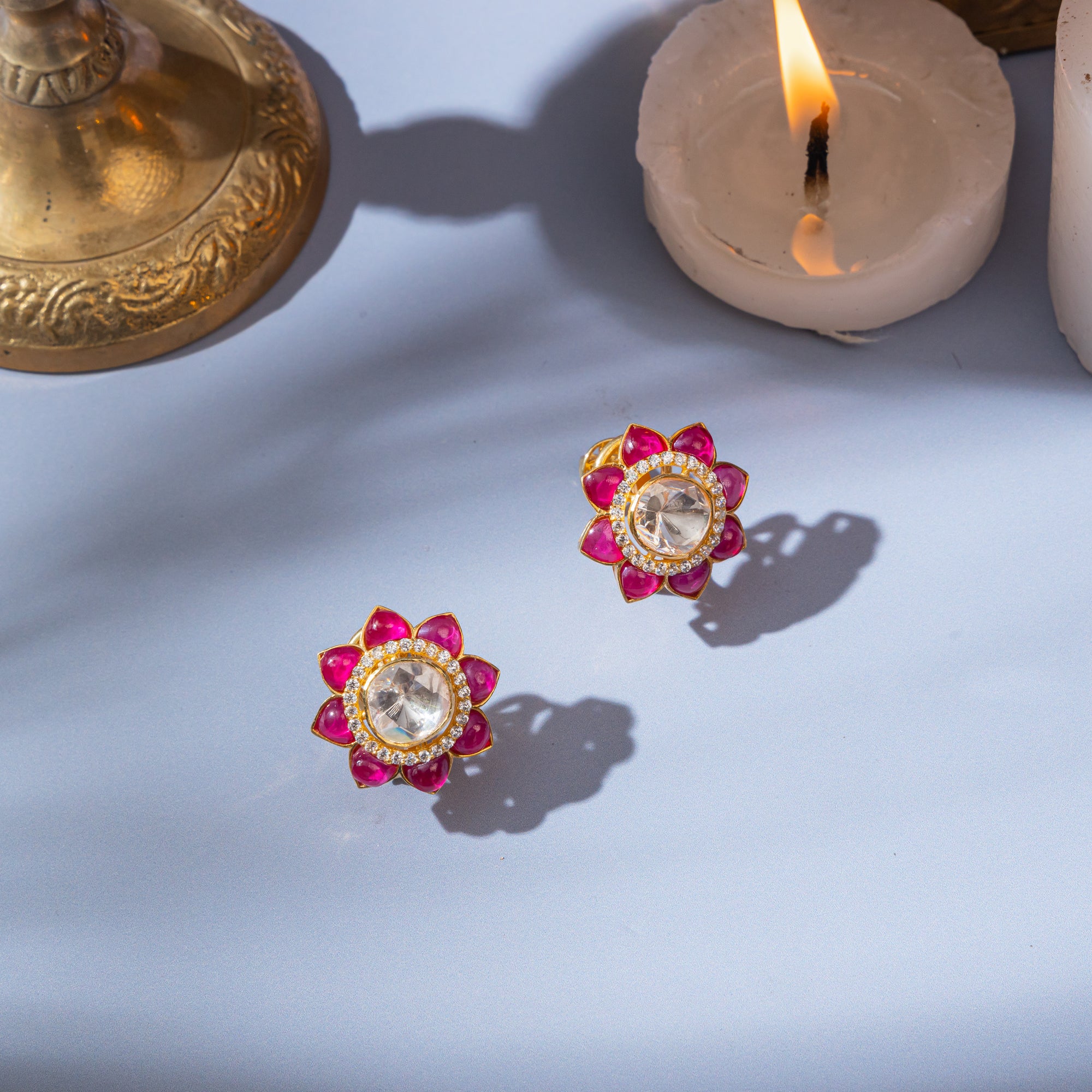 Ruby red stud earrings featuring a central high-quality polki-style gem surrounded by smaller ruby red stones in a sunflower pattern.