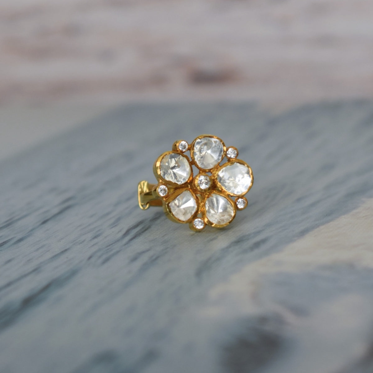 Gold-plated silver ring featuring a delicate floral motif encrusted with a moissanite stone. The ring has a flexible design.