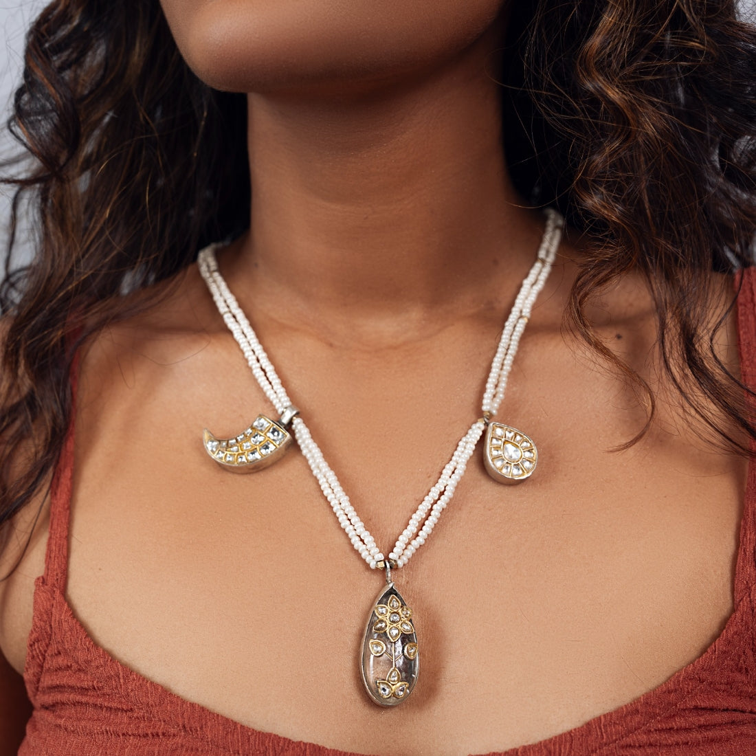 Jadau long necklace featuring a grey center stone with polki detailing, flanked by claw and pear-shaped charms. Delicate pearl strands complete the design.