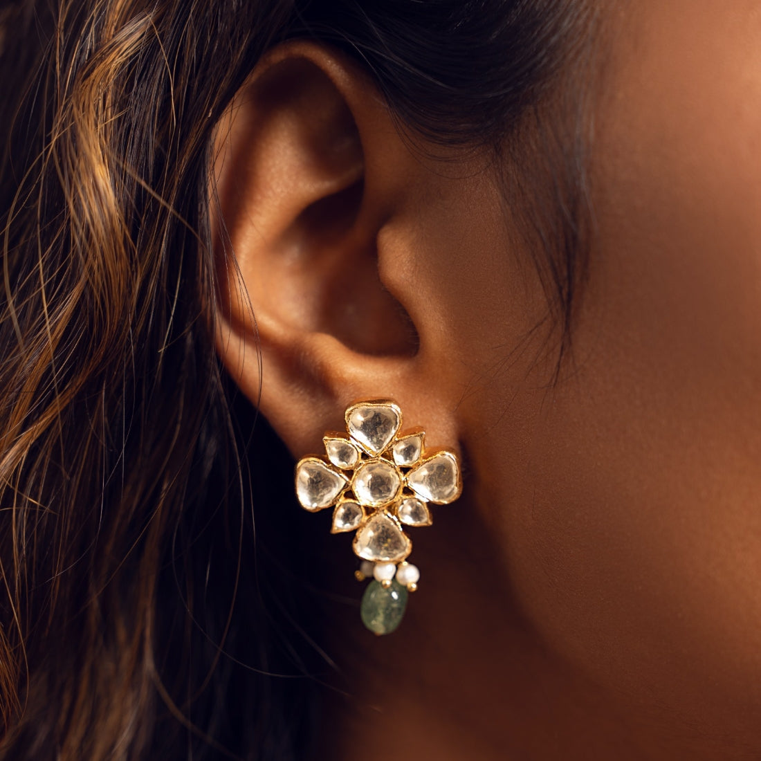 Silver stud earring featuring a floral motif with polki detailing, a pastel green bead, and cascading pearls.